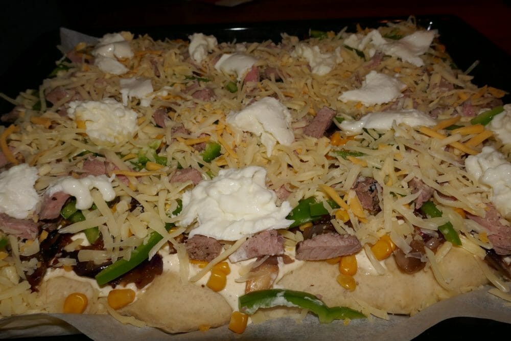 Hvit pizza med karamellisert løk og biffrester før steking